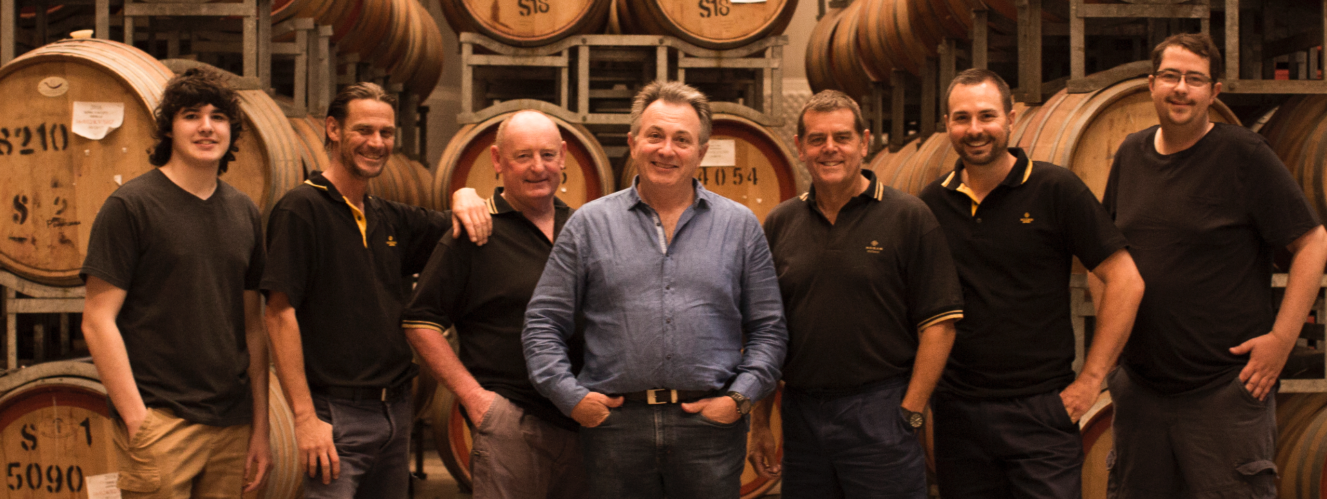 Nugan Estate team Matthew Nugan with types of red wine and nugan estate's best white wines barrelled behind them.